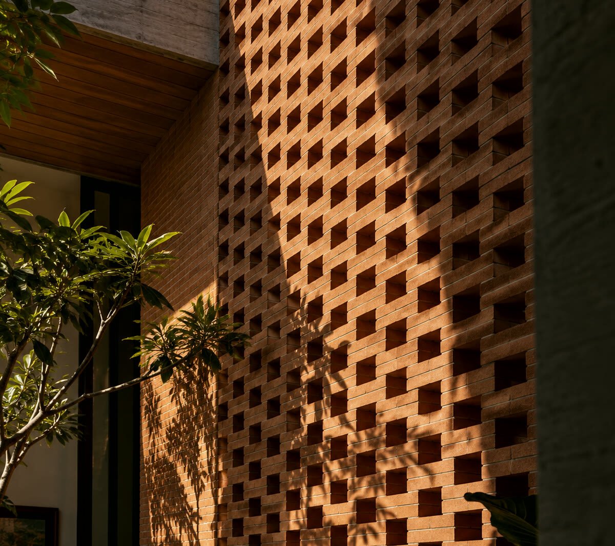 Courtyard house at dusk with a central reflecting pool, perforated brick screen and warm interior light